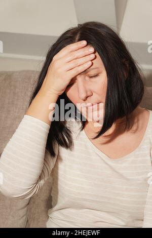Ältere Frau mittleren Alters mit Kopfschmerzen, Migräne. Frau in Schmerzen, traurig, müde, gestresst. Stockfoto