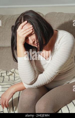 Ältere Frau mittleren Alters mit Kopfschmerzen, Migräne oder Depressionen. Frau in Schmerzen, traurig, müde, gestresst. Konzept der Trauer. Stockfoto