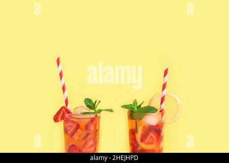 Erdbeerlimonade mit Eiswürfeln, Zitrone und Minze auf gelbem Hintergrund. Erfrischender Cocktail im Sommer. Stockfoto