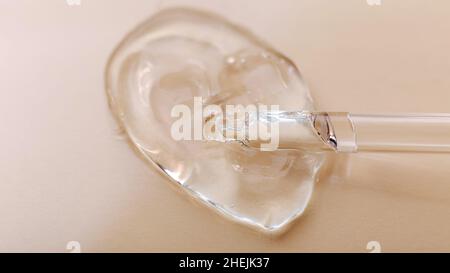Transparentes Gel-Hyaluron-Serum in Pipette auf beigem Hautton-Hintergrund. Wasser Textur Gel Oberfläche von kosmetischen Produkt für die Gesundheit der Haut Stockfoto