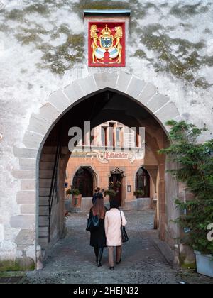 Zug, Schweiz - 31. Dezember 2021: Die Menschen betreten durch das Eingangstor der Mauern der mittelalterlichen Stadt Zug in der Schweiz mit dem Stadtmantel o Stockfoto