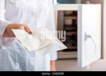 Frau halten Maniküre Pediküre Kosmetologie Instrumente Werkzeuge nach der Reinigung in Autoklaven Sterilisationssystemen für Desinfektion Schere in Craft Bag Stockfoto