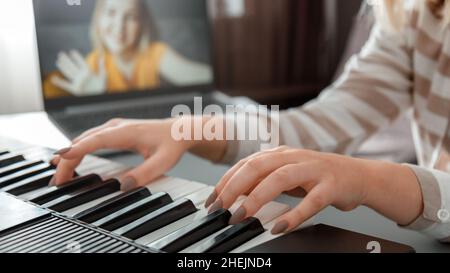 Frau, die während eines Videoanrufs über einen Laptop Klavier spielt. Weibliche Hände Musiker Pianist verbessert die Fähigkeiten Klavier online Unterricht mit Lehrer spielen. Online Stockfoto