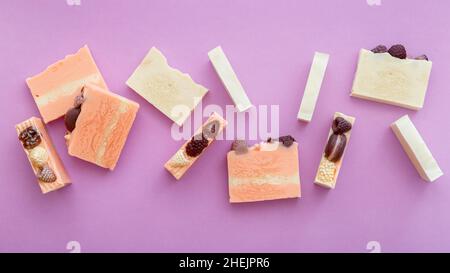 Natürliche handgemachte Seifenstücke flach Lay Zusammensetzung. Viele duftende handgemachte Spa Bio rosa weiße Seifenstücke. Hausgemachte Beauty-Produkte auf lila Stockfoto