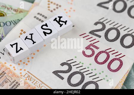 Die Formulierung „Zysk“ wurde mit „Profit“ und vielen polnischen Banknoten übersetzt. Foto aufgenommen unter künstlichem, weichem Licht Stockfoto