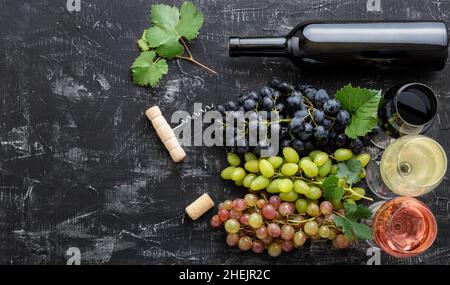 Sortiment verschiedene Arten von Wein und Sorten. Verkostung von weißem Rosé-Rotwein in Gläsern in der Nähe von weißen rosa und schwarzen Trauben, Rotwein-Flasche auf Stockfoto