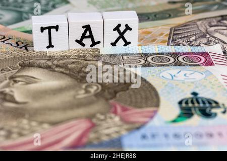Die Formulierung „Steuer“ wurde mit „Steuer“ und vielen polnischen Banknoten übersetzt. Neue Steuervorschriften in Polen ab 2022. Foto aufgenommen unter künstlichem, weichem Licht Stockfoto