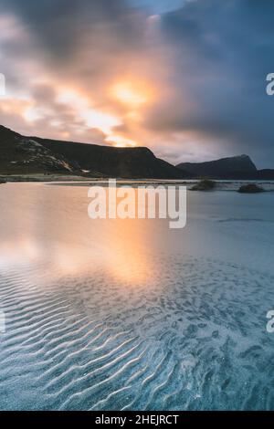 Sonnenaufgangslicht, das sich im kalten, transparenten Meer am Haukland-Strand, Leknes, Vestvavoy, Nordland, Lofoten-Inseln, Norwegen Stockfoto