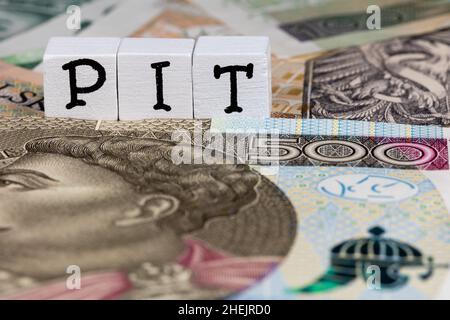 Die Formulierung „PIT“ wurde mit „Körperschaftssteuer“ und vielen polnischen Banknoten übersetzt. Neue Steuervorschriften in Polen ab 2022. Foto aufgenommen unter künstlichem, weichem Stockfoto