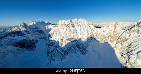 Luftaufnahme des klaren Winterhimmels über dem schneebedeckten Berg Sciora di Dentro, Val Bregaglia, Graubünden, Schweiz Stockfoto