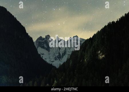Sternenhimmel über den Berggipfeln und Wäldern von Sciore, Val Bondasca, Val Bregaglia, Kanton Graubünden, Schweiz Stockfoto