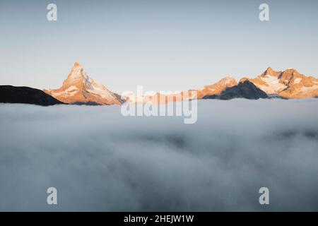 Matterhorn und Dent Blanche Berggipfel, die bei Sonnenaufgang aus dem Nebel aufsteigen, Luftaufnahme, Zermatt, Kanton Wallis, Schweiz Stockfoto