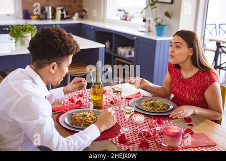 Glückliches biracial junges Paar genießen Mittagessen Datum am Esstisch in der Küche Stockfoto