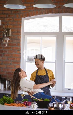 Glückliches biracial junges Paar genießen einen Tanz während der Zubereitung von Essen in der Küche Stockfoto