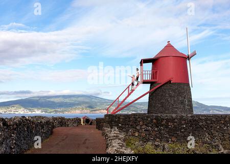 Portugal, Azoren, Pico Island, Criacao Velha, Moinho do Frade, Mutter und Sohn stehen auf einer Leiter an der traditionellen Windmühle in vulkanischen Weinbergen Stockfoto