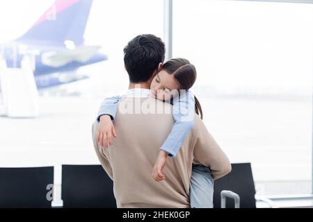Mädchen schläft auf der Schulter des Vaters in der Lounge am Flughafen Stockfoto