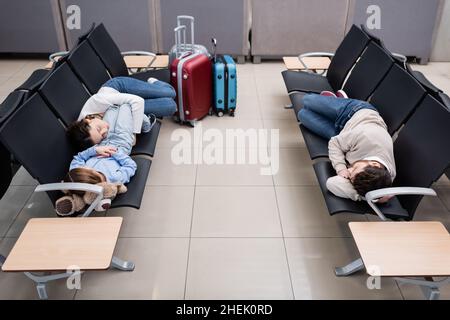 Familie schläft auf den Sitzen am Flughafen in der Abflughalle Stockfoto
