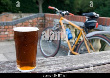 Ein Willkommens-Pint englisches bitteres Bier nach einer Mountainbike-Session. Vor einem englischen Pub (öffentliches Haus) in Surrey Stockfoto
