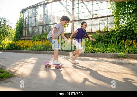 Konzentriertes Kid Skateboarding, unterstützt von seinem Freund Stockfoto