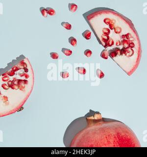 Kreatives Granatapfel-Layout aus Samen und Granatapfel auf pastellblauem Hintergrund aufgeschnitten. Minimalismus bei frischen Früchten. Stockfoto