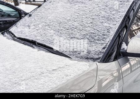 An einem Wintertag war die Windschutzscheibe eines gefrorenen Autos bedeckt und der Rückspiegel war mit Eis und Schnee bedeckt. Nahaufnahme. Stockfoto