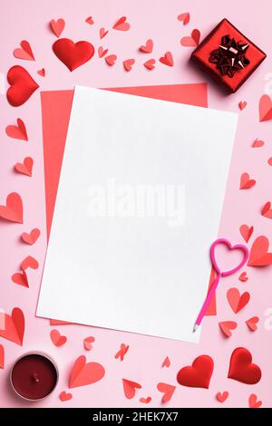 Valentinstag-Konzept mit Liebesbrief. Weißes Blatt Papier Geschenk Kerze Herzen auf rosa Hintergrund. Stockfoto