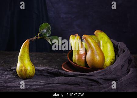 Ländliches Stillleben, dunkle Fotografie mit niedriger Tonart - Ansicht einer Konferenzbirne in Tontellern, Nahaufnahme einer Gruppe von Birnen mit selektivem Fokus Stockfoto