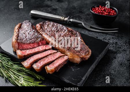 Gegrilltes Rinderfilet oder Rinderfilet auf Marmorplatte. Schwarzer Hintergrund. Draufsicht Stockfoto