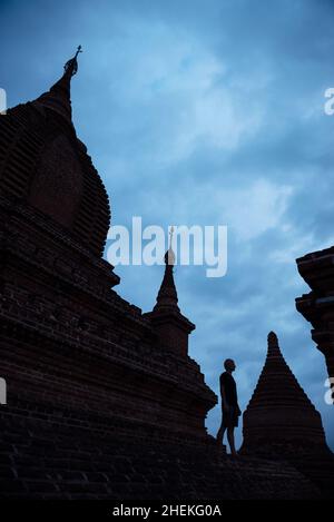 Mann, der nachts auf dem Dach der Pagode über dem dunkelblauen Himmel in Myanmar steht. Touristenattraktion. Stockfoto