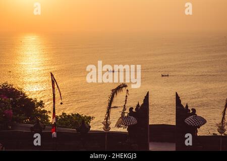 Traditionelle balinesische Boote, die beim Sonnenuntergang segeln, vom Pura Luhur Uluwatu aus gesehen, Uluwatu-Tempel ein balinesischer Hindu-Seetempel auf dem Hügel, Bali, in Stockfoto