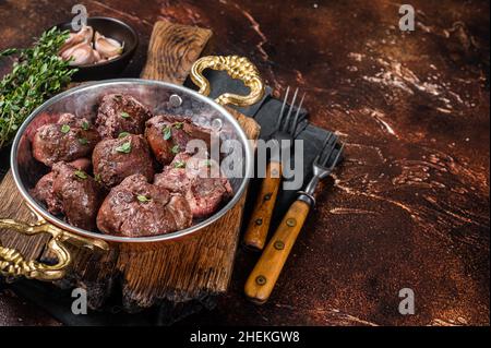 Geröstete Rinderniere, Schlachtnebenfleisch in Pfanne mit Kräutern. Dunkler Hintergrund. Draufsicht. Speicherplatz kopieren Stockfoto