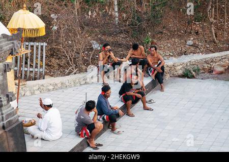 Bali - Indonesien - 10.21.2015: Männliche Kecak-Tänzer tragen rote Hibiskusblüten auf ihren Ohren und bereiten sich auf den Auftritt im Pura Luhur Uluwatu Amphi vor Stockfoto