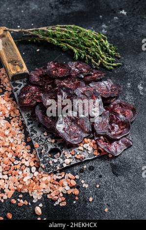 Trockene Salami-Wurst auf einem Metzgertisch. Schwarzer Hintergrund. Draufsicht Stockfoto