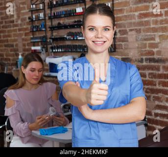 Junge lächelnde Mädchen Manikuristin steht in modernen Nagelstudio Stockfoto