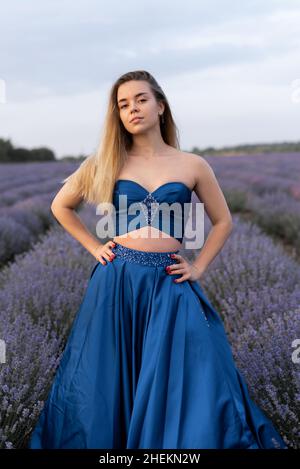 Schönes Mädchen in einem blauen Hochzeitskleid steht in einem Lavendelfeld. Stockfoto