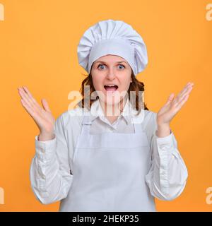 Enthusiastische Köchin mit einem fröhlichen Lächeln auf ihrem Gesicht auf einem Studiohintergrund Stockfoto