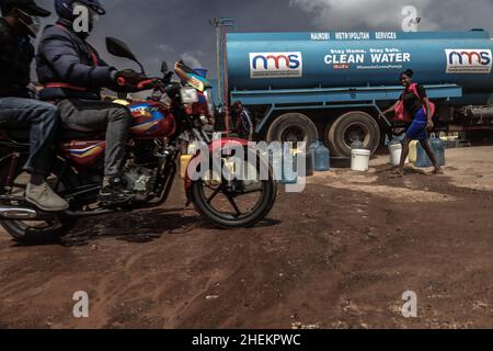 Nairobi, Kenia. 11th Januar 2022. Ein Motorrad, das während des Wassermangels an einem Wasserfahrzeug vorbeifährt.die meisten Bewohner von Nairobi erleben weiterhin den täglichen Mangel und Mangel an Wasser. In den Slums von Kibera haben die Nairobi Metropolitan Services (N.M.S) die Verantwortung übernommen, den meisten Bewohnern in einigen armen Gemeinden den Zugang zu kostenlosen und häufigen Trinkwasserdiensten zu ermöglichen. Kredit: SOPA Images Limited/Alamy Live Nachrichten Stockfoto