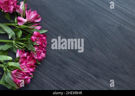 Rand von Alstroemeria Blumen auf einem dunklen Holzhintergrund mit Kopierraum Stockfoto