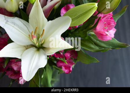 Frische Lilie und rosa Alstroemeria Blumenstrauß auf einem dunklen Holzhintergrund mit Kopierraum Stockfoto