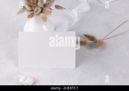 Leere Karte Mockup, Hochzeit Schreibwaren Einladung auf grauen Stein Tisch Hintergrund mit weißem Band, feminine Blog. Minimalistisches Modell, Verhältnis 5x3,5, Simp Stockfoto
