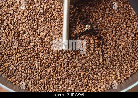 Geröstete Kaffeebohnen nach dem Rösten auf der Kühlplatte des Backofens mischen. Industrielle Bohnen rösten. Draufsicht Stockfoto