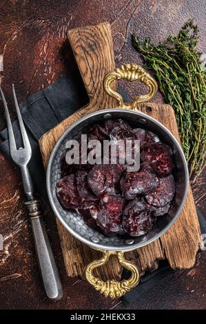 Hausgemachte Wildwurst.mit Kräutern in einer Pfanne. Dunkler Hintergrund. Draufsicht Stockfoto