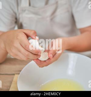 Junge Hände trennen das Eiweiß vom Eigelb für den Kuchen Stockfoto