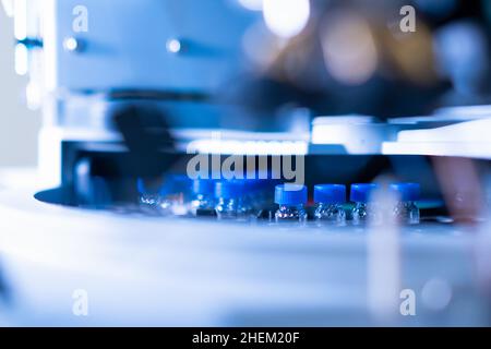 HPLC-Glasfläschchen mit blauen Kappen im automatischen Probennehmer. Chemische Analyse von Pflanzen und menschlichen Proben Stockfoto