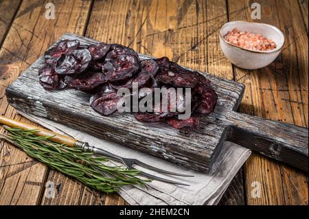 Wildfleischwurst mit Rosmarin auf einem Schneidebrett. Holzhintergrund. Draufsicht Stockfoto