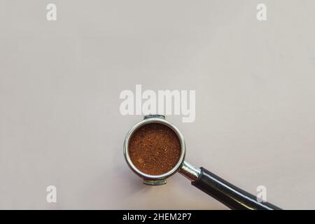 Portafilter mit gemahlenem Kaffee auf hellgrauem Hintergrund. Draufsicht. Stockfoto