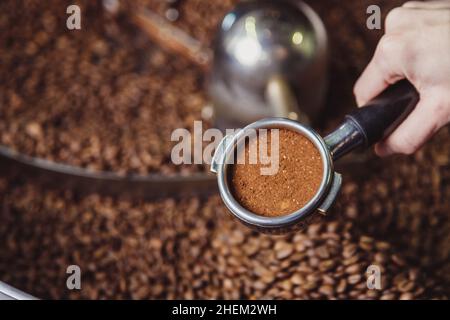 Nahaufnahme Mädchen Hand hält einen Portafilter mit gemahlenem Kaffee Stockfoto