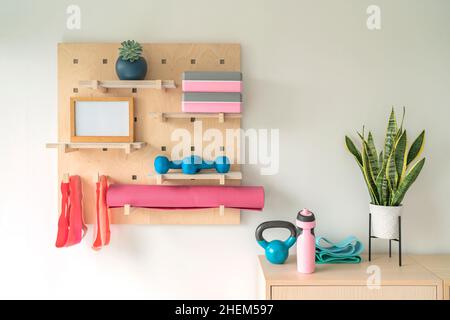 Workout Fitness zu Hause Fitnessstudio organisierte Regale für Pilates-Geräte. Holzpegboard speichert Widerstandsbänder, Gewichte, Yoga-Blöcke, motivierend Stockfoto
