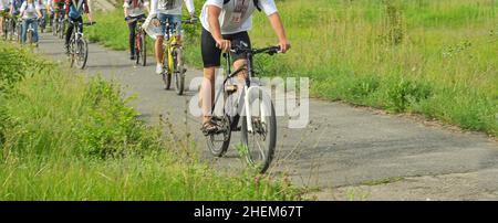 City-Radtour in der Ukraine, Menschen ohne Gesichter in legerer Kleidung, Asphalt und grünes Gras. Stockfoto