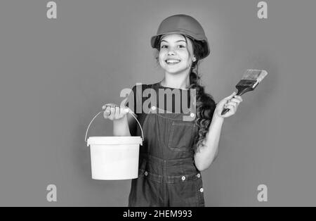 Fröhliche Kinderarbeiter mit Gebäude Uniform und Malerei Eimer und Pinsel, kreative Arbeit Stockfoto